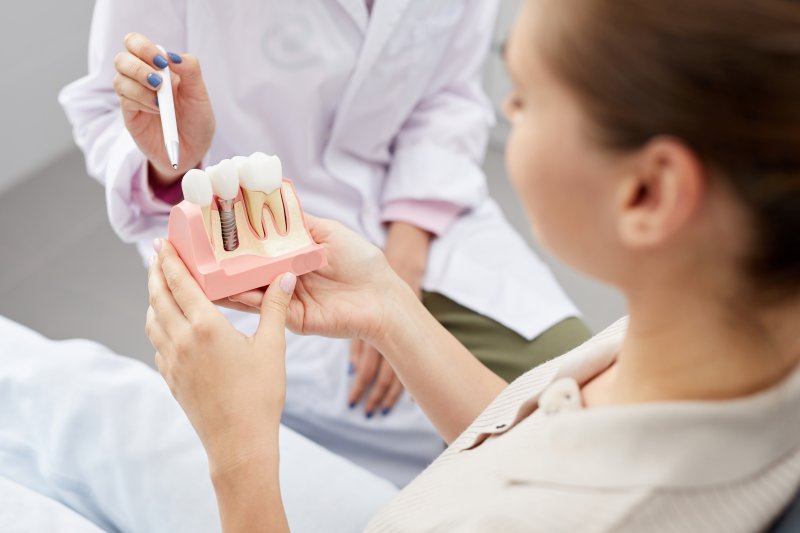 dentist showing off a model of a dental implant