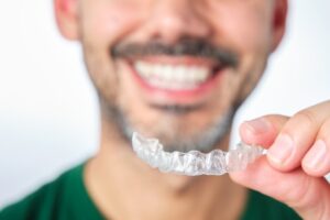 Man smiling while getting ready to put his Invisalign tray in