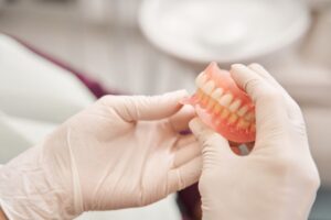 White gloved hand holding denture in close-up.