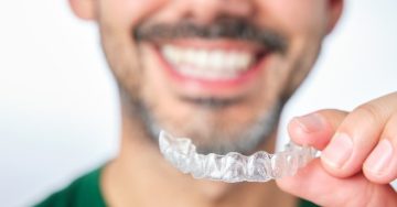 Man smiling while getting ready to put his Invisalign tray in