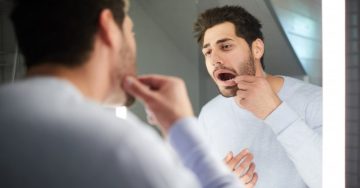 Man looking in the mirror for gum bumps
