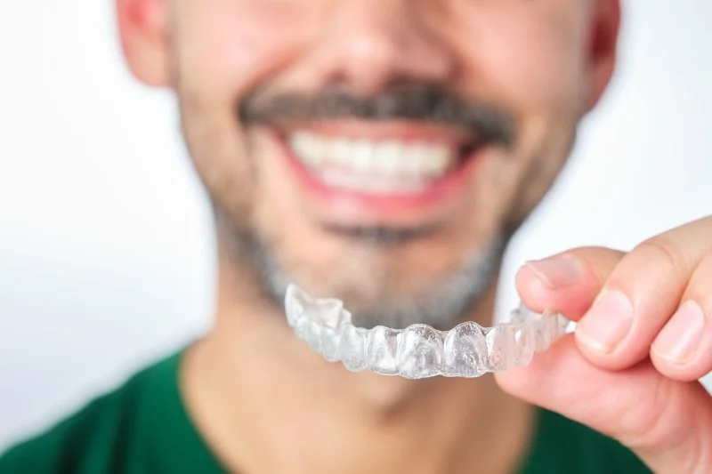 Man smiling while getting ready to put his Invisalign tray in